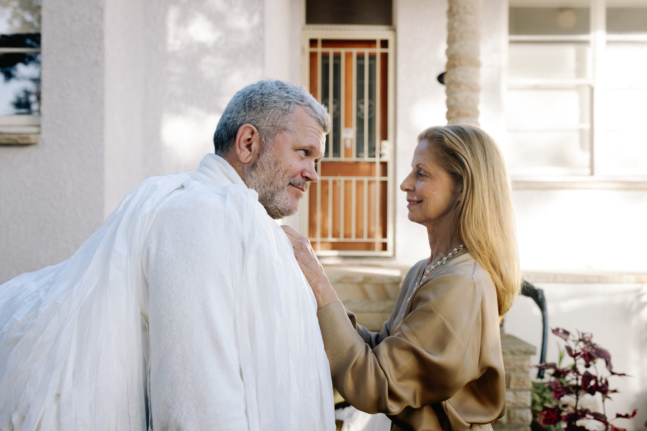 Pleasant Avenue — a couple outside a house, with the man wrapped in white material
